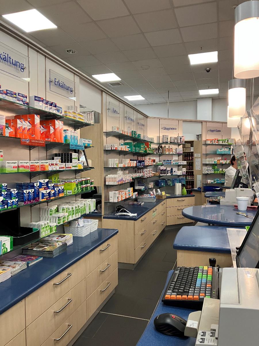 Kassenbereich, Glasabtrennung und Regalen mit Medikamenten.